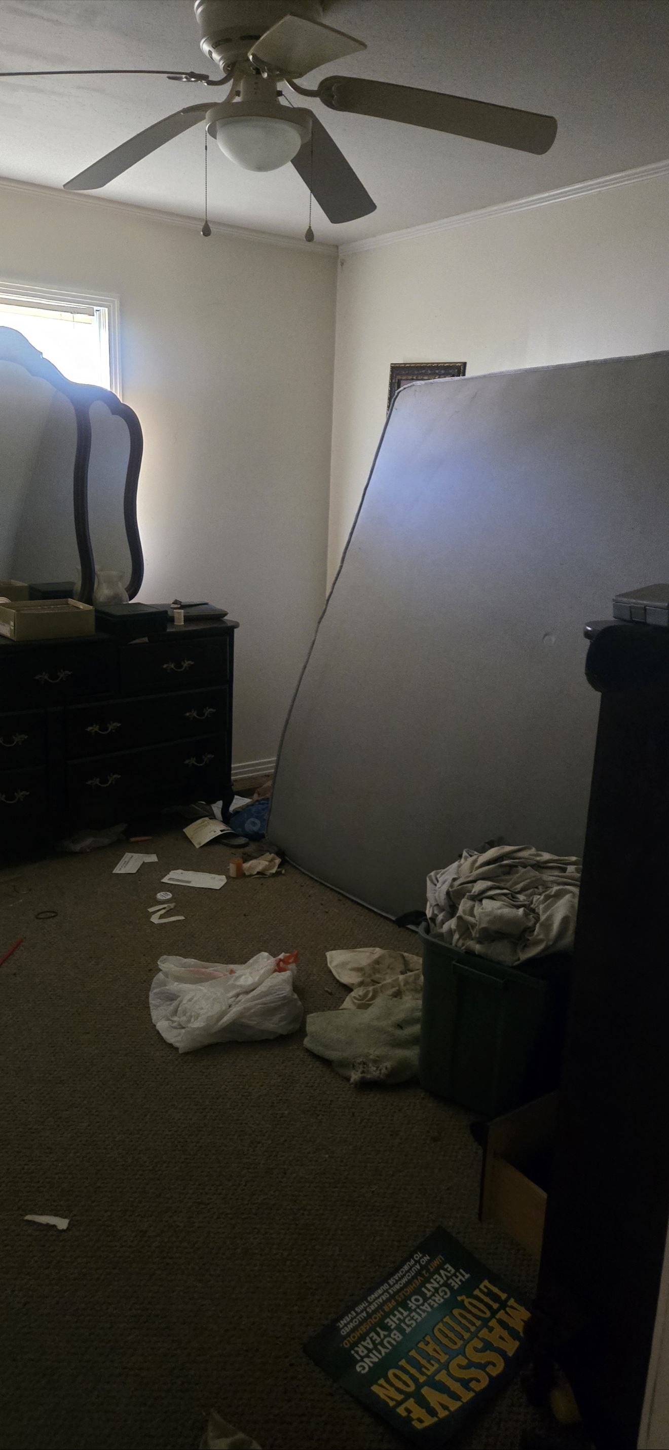 Bedroom with a large mattress, dresser, bins, and loose debris before removal